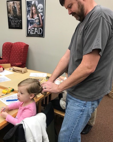 Dad learning how to fix daughter's hair