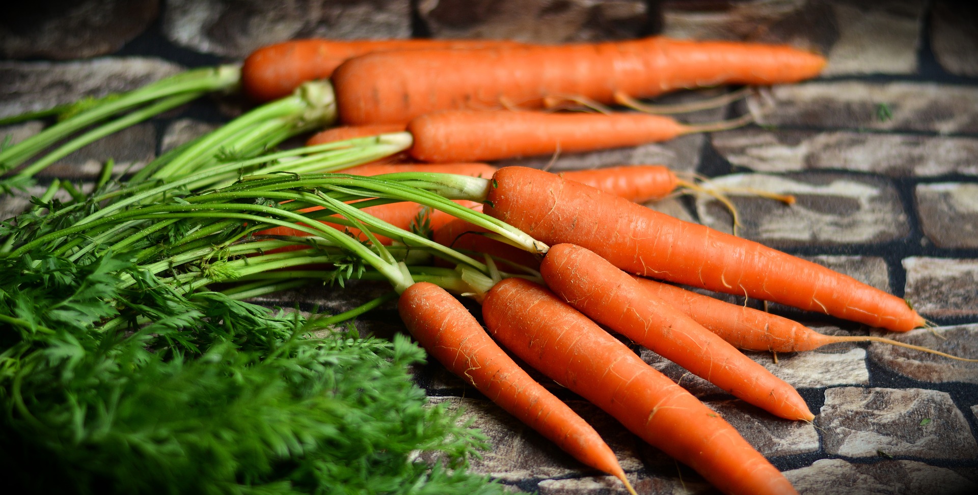 9 orange carrots against a stone background. 