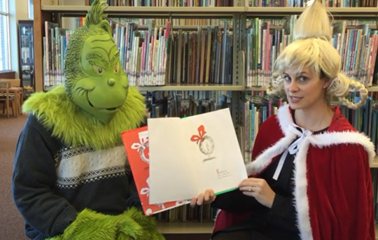 The Grinch and Cindy Lou reading "How the Grinch Stole Christmas"