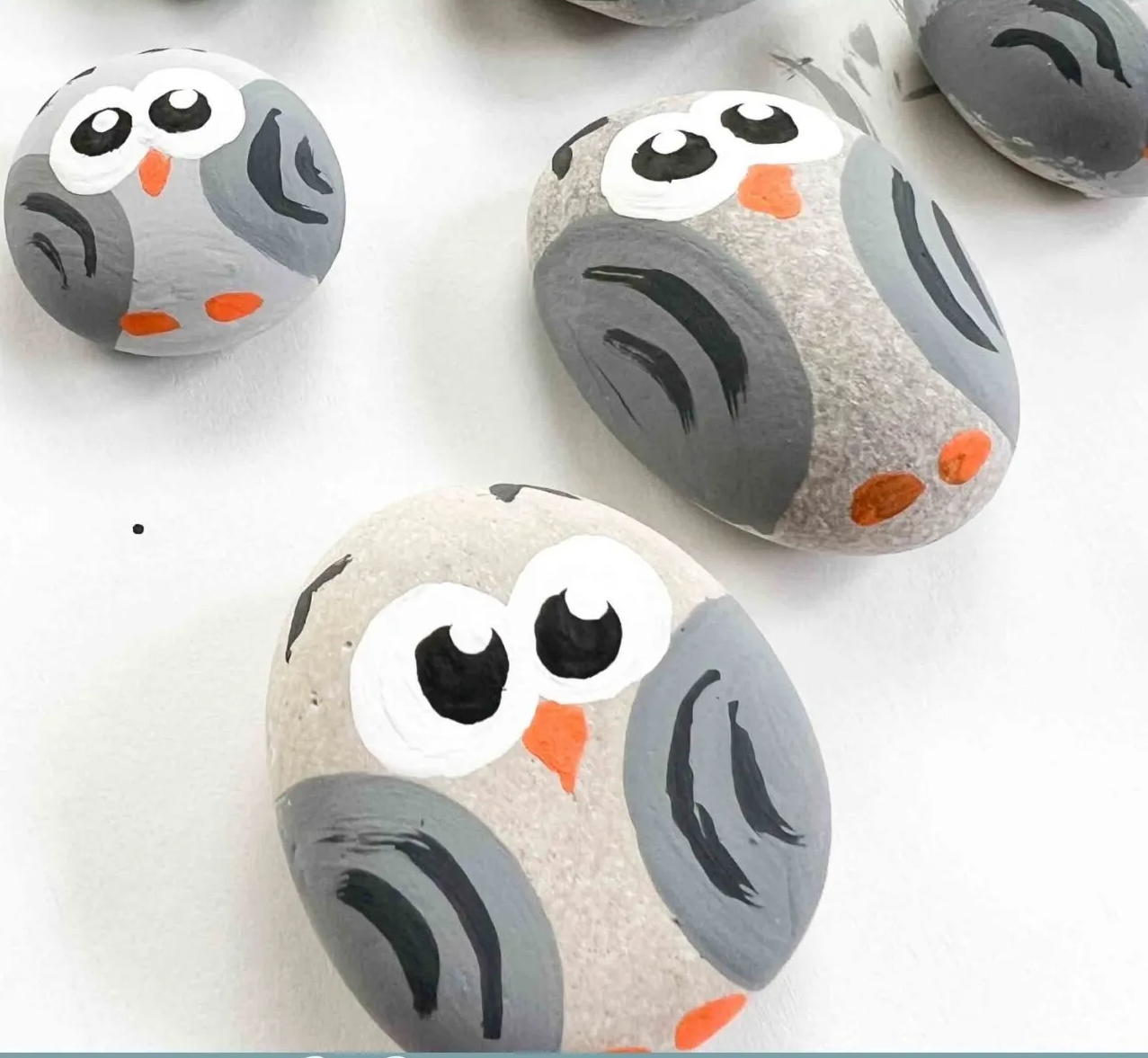 Three grey painted rocks that look like owls. 