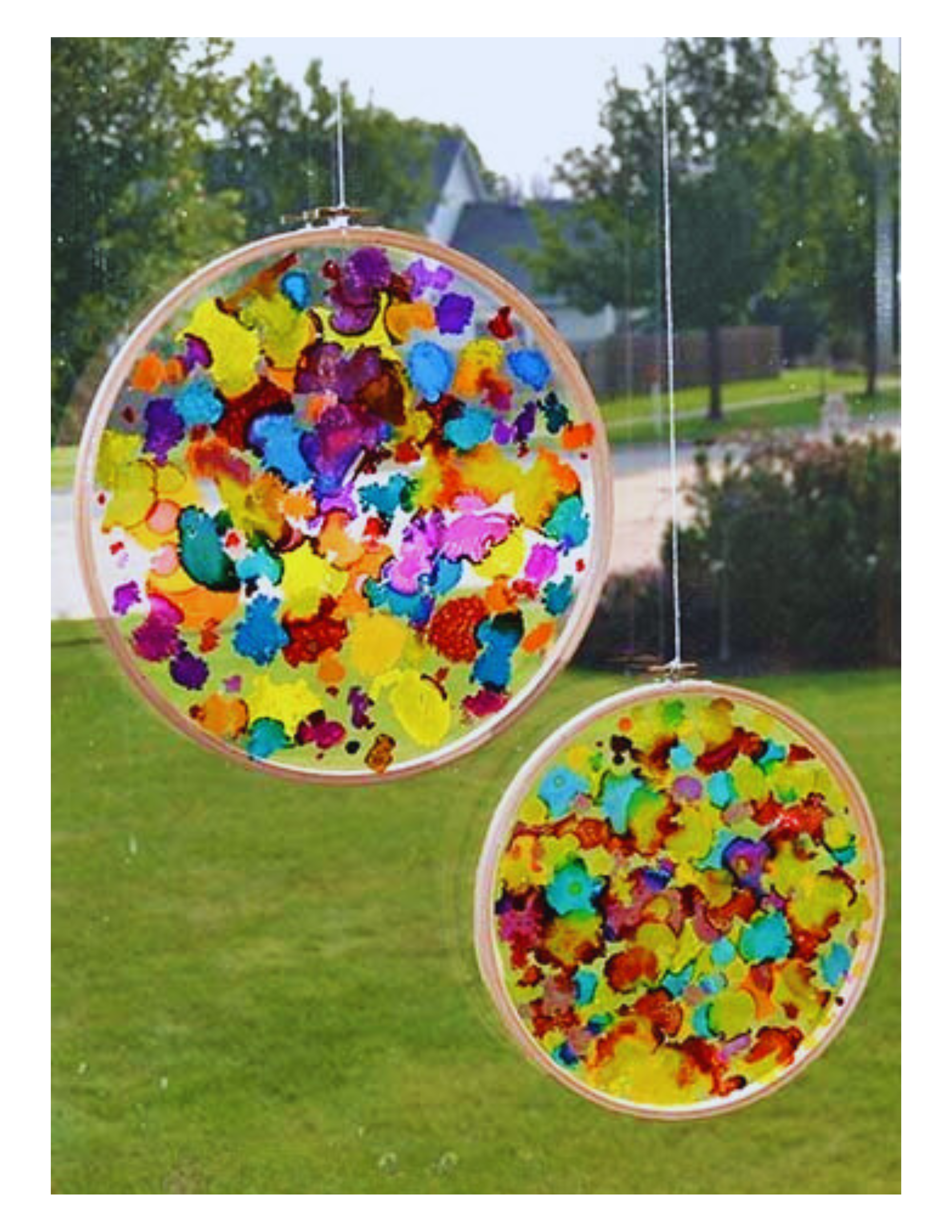 two multicolor sun catcher against a landscape scene. 