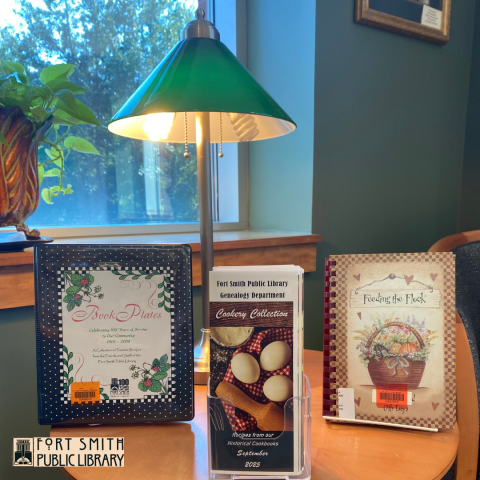Arkansas cookbooks and brochure under a green table lamp