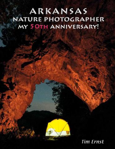 lighted yellow tent under a rock arch at night on the front of Tim Ernst book "Nature Photographer"
