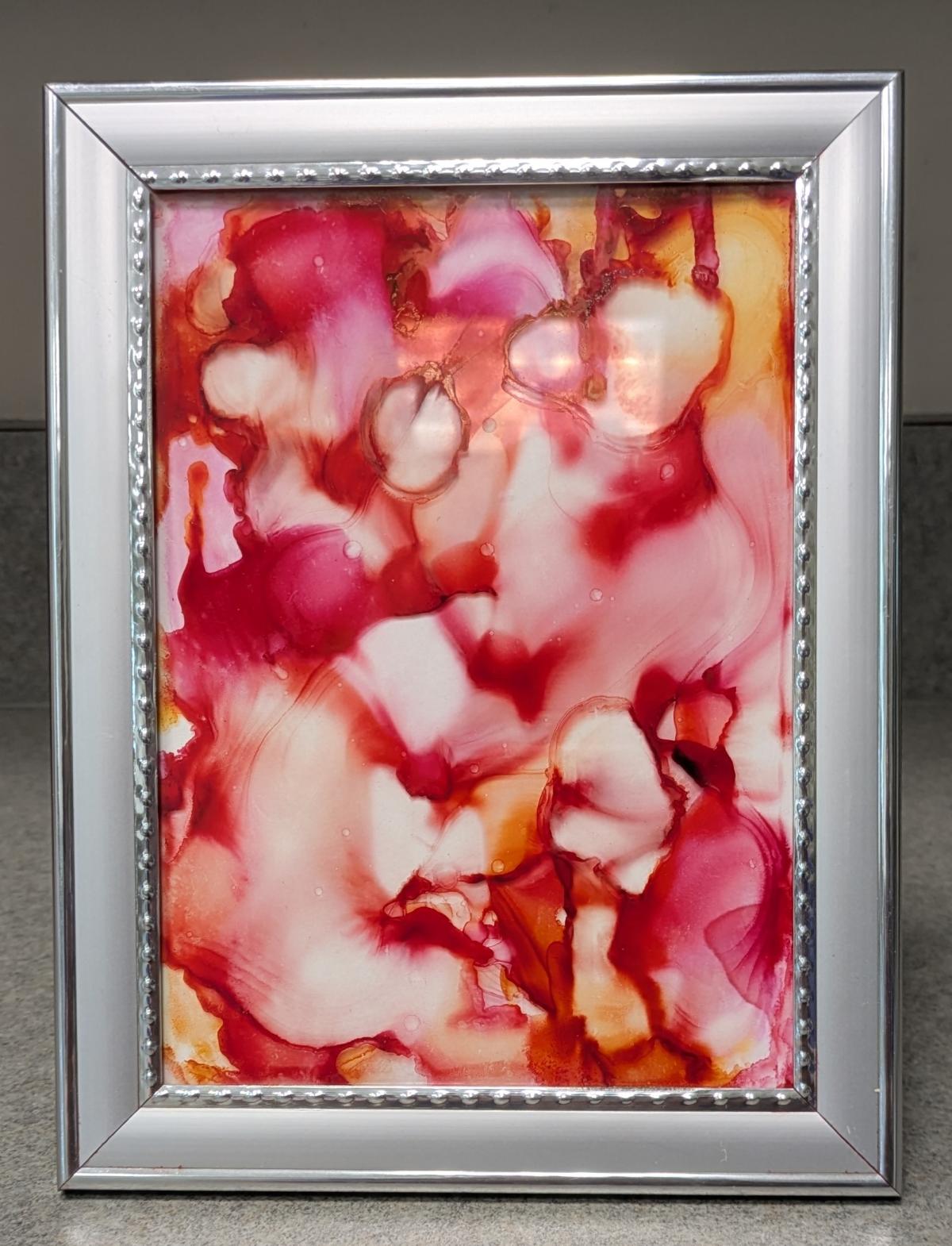 pink and orange fired ink painting in a silver frame